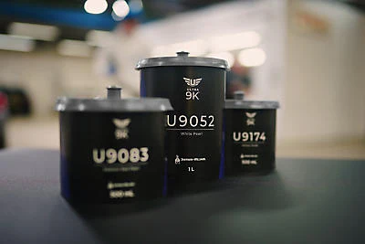 Three black cylindrical containers with product codes U9083, U9052, and U9174 displayed on a surface in a retail setting