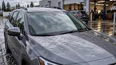 Silver SUV with water droplets parked at auto service facility with garage bays visible