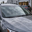 Silver SUV with water droplets parked at auto service facility with garage bays visible