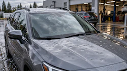 Silver SUV with water droplets parked at auto service facility with garage bays visible