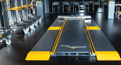 Industrial 3D printer with yellow and black frame in modern workshop with tools and storage