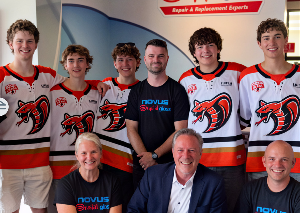 Team photo of young hockey players in red and white jerseys with adult staff members wearing NOVUS branded apparel
