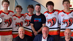 Team photo of young hockey players in red and white jerseys with adult staff members wearing NOVUS branded apparel