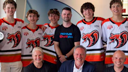 Team photo of young hockey players in red and white jerseys with adult staff members wearing NOVUS branded apparel