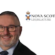 Professional headshot of a man wearing glasses and dark suit with Nova Scotia Legislature logo
