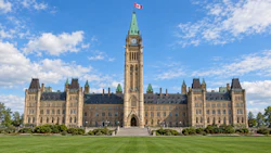 Parliament of Canada Centre Block with copper roof and clock tower under blue sky with clouds