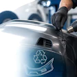 Technician using heat gun on car bumper with recycling symbol decal