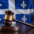 Wooden gavel and sound block in front of Quebec flag with vehicle background