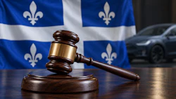 Wooden gavel and sound block in front of Quebec flag with vehicle background
