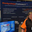Woman presenting BodyshopConnect software solution at trade show booth with blue banner display