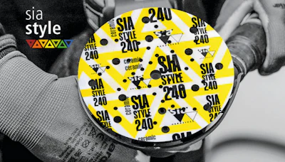 Person holding yellow SIA Style 240 branded disc with black polka dots and repeating text pattern