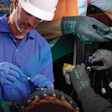 Industrial workers wearing blue AppFlex safety gloves assembling or inspecting automotive components on a production line