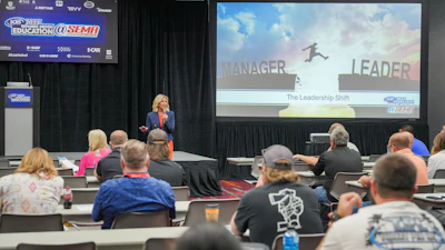 Professional speaker presenting 'The Leadership Shift' at SEMA education conference with audience seated at tables.
