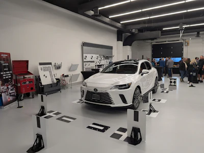 White Toyota Corolla on display in a modern showroom with visitors and exhibition barriers