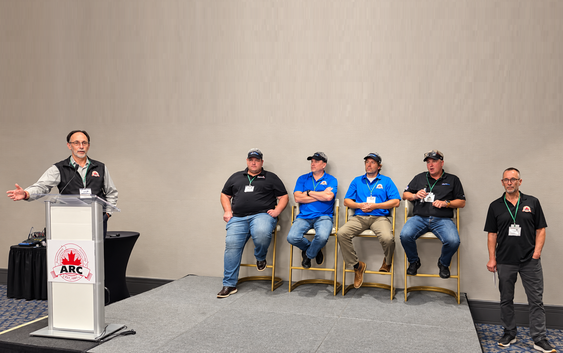 Panel discussion at ARC conference with speaker at podium and five seated panelists