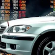 Silver SUV with dynamic water splash effect and stock market data overlay in background