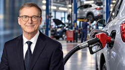 Professional man in business suit and glasses at automotive service center with vehicles and mechanics in background