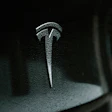 Tesla T emblem mounted on vehicle door with metallic finish and frost-like texture
