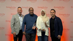 Four professionals posing together at a Simplicity branded corporate event with coral gradient backdrop