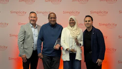 Four professionals posing together at a Simplicity branded corporate event with coral gradient backdrop
