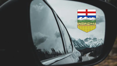 Alberta provincial shield reflected in car side mirror with snowy mountain landscape