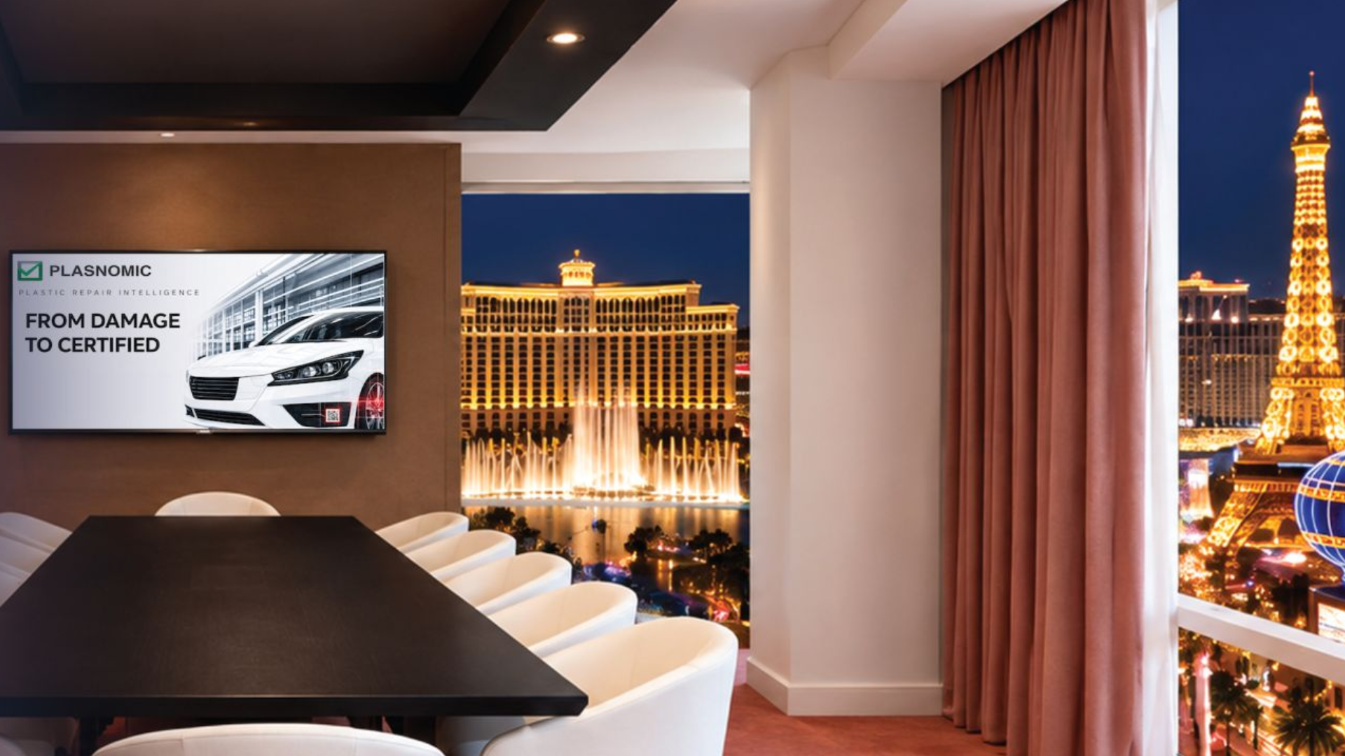 Modern conference room with Plasnomic logo on screen overlooking Las Vegas Strip at night