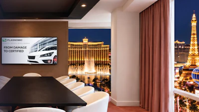 Modern conference room with Plasnomic logo on screen overlooking Las Vegas Strip at night