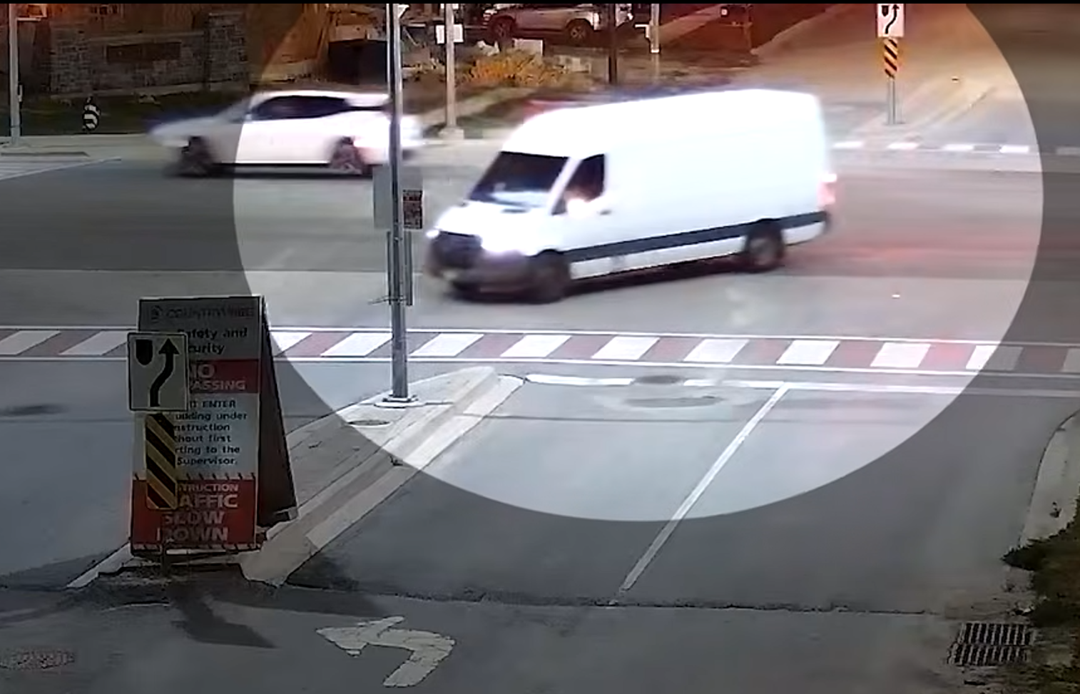 White delivery van crossing intersection at crosswalk with sedan visible in background
