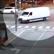 White delivery van crossing intersection at crosswalk with sedan visible in background