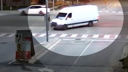 White delivery van crossing intersection at crosswalk with sedan visible in background