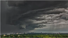 Dramatic storm clouds gathering over a residential cityscape with dark skies and rain shafts