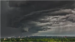 Dramatic storm clouds gathering over a residential cityscape with dark skies and rain shafts