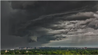 Dramatic storm clouds gathering over a residential cityscape with dark skies and rain shafts