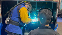 Welder performing welding demonstration with bright arc light and blue and yellow protective equipment at trade show or educational event