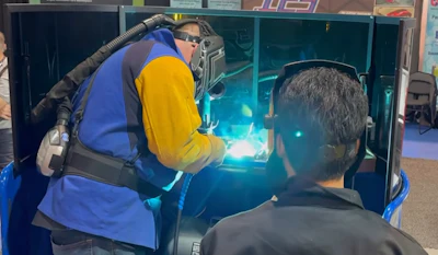 Welder performing welding demonstration with bright arc light and blue and yellow protective equipment at trade show or educational event