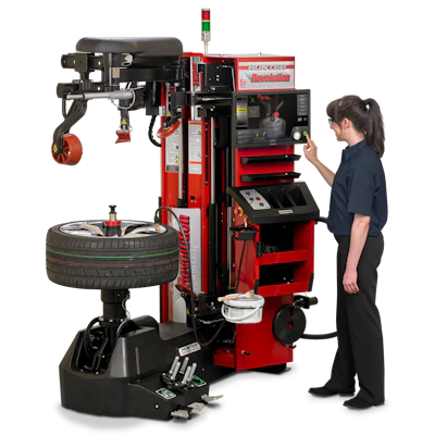 Technician operating a red Coats tire changer machine with mounted tire and automatic arm system